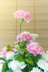 Pink and white bouquet carnation flowers on table with wooden curtain background
