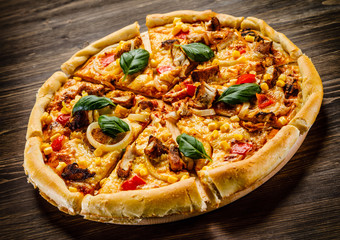 Pizza with chicken and vegetables on wooden background