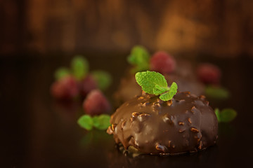 Chocolate cakes witn nuts, mint and ruspberry on dark background, bird milk in chocolate glaze