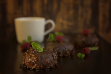 Chocolate cakes witn nuts, mint and ruspberry on dark background, bird milk in chocolate glaze