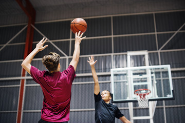 Two teenage boys playing basketball together on the court
