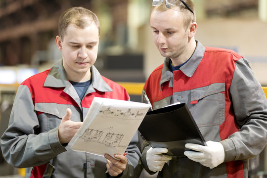 Industrial manufacturing workers reading engineering drawing in factory workshop, consulting and solution
