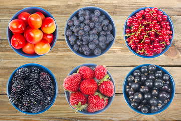 Berries on Wooden background, bowl of Cherry, currant, blueberries, gooseberries, raspberries, blackberries, strawberries, apricots.