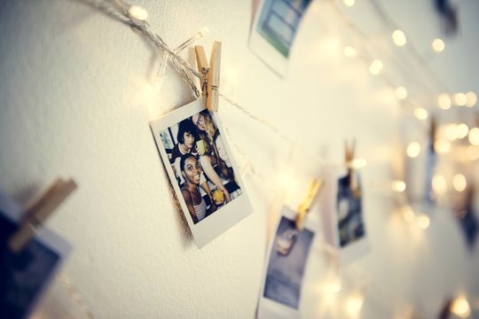 Photos hanging with decoration lights on the white wall