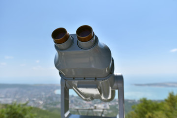 Stationary binoculars set high in the mountains to look at the bay and the sea