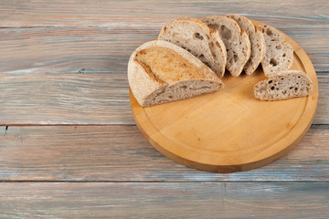 Many mixed breads and rolls of baked bread on wooden table background.
