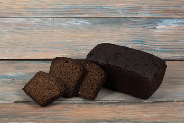 Many mixed breads and rolls of baked bread on wooden table background.