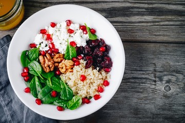 Green salad spinach bowl with quinoa, pomegranate, walnuts, feta cheese and dried cranberries.
