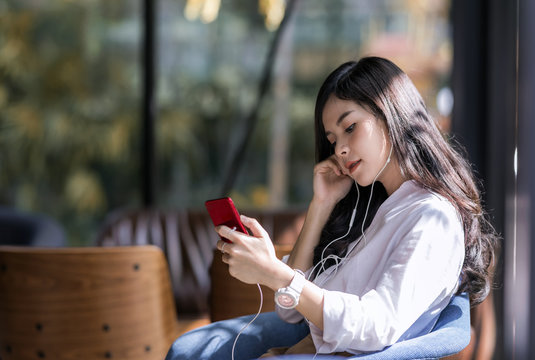 asian woman holding smartphone and listening  music from her phone