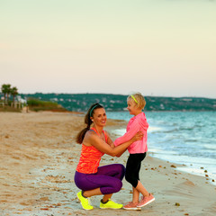 happy mother and child on seashore in evening having fun time