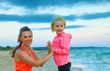 smiling mother and daughter on beach in evening having fun time