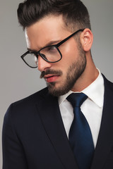 handsome businessman with eyeglasses focusing on something down to side