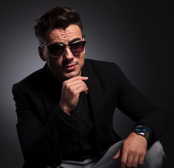 Obraz premium young fashion man with sunglasses sitting and thinking