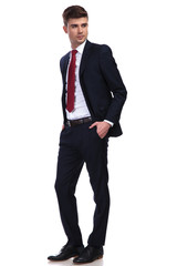 relaxed businessman with arms in pockets looks to side
