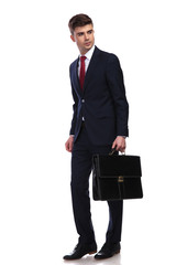 businessman walking with briefcase in hand looks to side