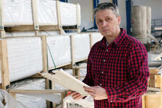 Man with folder management in the hands of the warehouse . Logistics concept of export import against the background of the warehouse .