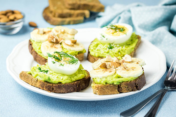 Bread with smashed avocado, eggs, banana and nuts. Selective focus, space for text.