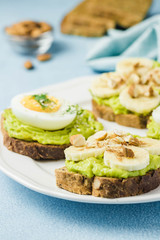 Toasts with avocado, eggs, banana and nuts. Selective focus, space for text, close up.