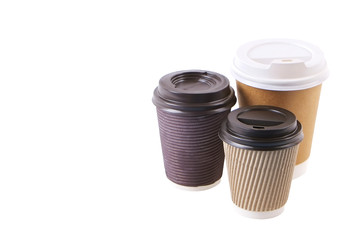 Three brown carton double walled paper cups, different sizes, take out, coffee to go. Disposable eco-friendly cardboard mugs for hot beverages w/ cap, isolated white, background, close up, copy space.