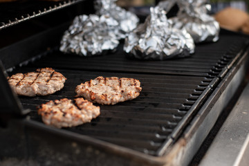 Burgers are grilled with baked potatoes