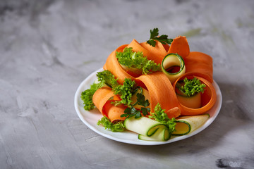 Artistically served vegetable salad with carrot, cucumber, letucce over white background, selective...