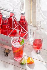 Red summer drink in bottle with mint leaf
