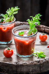 Tasty bloody mary cocktail with tomatoes on old barrel