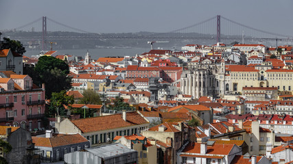 Fototapeta na wymiar Red tiled rooftops with the bridge creating a line on the horizon of Lisbon