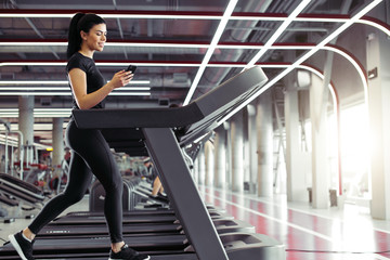 fit Sporty business woman texting on smartphone while jogging on treadmill