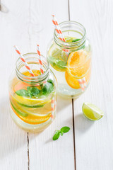 Water with mint leaves and citrus fruits on white table