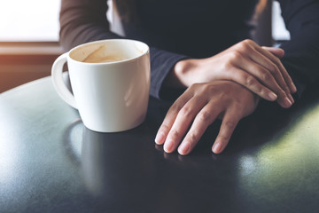 Closeup image of a woman holding hand and drinking hot coffee in cafe