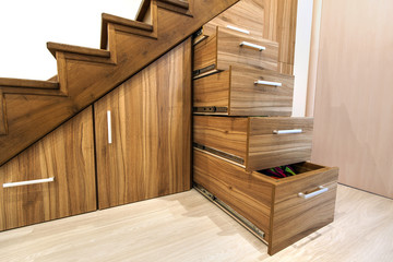 Modern architecture interior with  luxury hallway with glossy wooden stairs in modern storey house. Custom built pullout cabinets on glides in slots under stairs