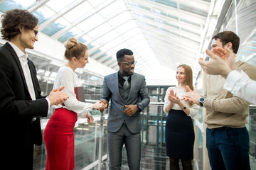 multiracial businessmen making agreement, their colleague standing near by