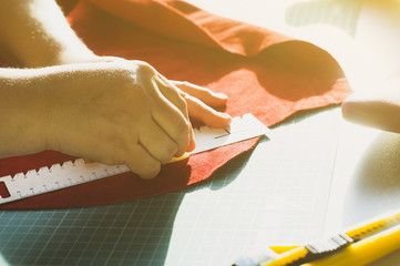 Hands of the master. Marking and slicing red leather for making bags, purses or shoes.