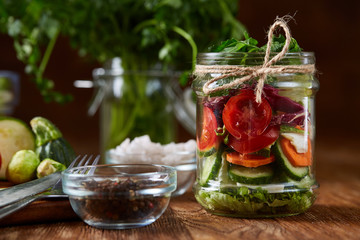 Fresh vegetable salad and ripe veggies on cutting board over wooden background, close up, selective focus