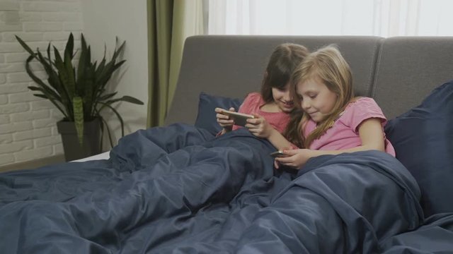 kids smartphone addiction. two little girl playing gadget games