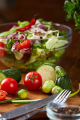 Fresh vegetable salad and ripe veggies on cutting board over wooden background, close up, selective focus