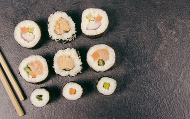 Various kinds of sushi on the dark background.