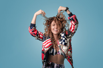 Portrait of a young girl with curly hair with eyes surprised. She holds his hair with his hands and laughs with joy, looks at the camera