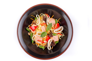 Egg noodles with squid under teriyaki sauce, isolated on white background. Egg noodles in a black plate.