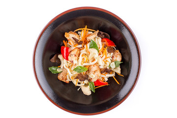 Wheat noodles with pork and vegetables under teriyaki sauce, isolated on white background. Wheat noodles in a black plate.