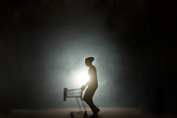 portrait of a man pushing an empty shopping cart isolated on black background. after shopping....