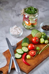 Fototapeta na wymiar Fresh vegetable salad and ripe veggies on cutting board over white background, close up, selective focus