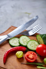 Fresh vegetable salad and ripe veggies on cutting board over white background, close up, selective focus