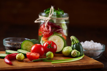 Fresh vegetable salad and ripe veggies on cutting board over wooden background, close up, selective focus