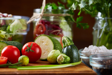 Fresh vegetable salad and ripe veggies on cutting board over wooden background, close up, selective focus