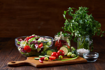 Fresh vegetable salad and ripe veggies on cutting board over wooden background, close up, selective focus