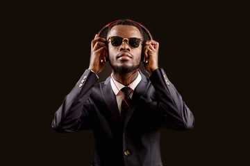 portrait of young businessman in sunglasses and stylish suit listening to music in the ears. like music. record the rap