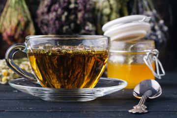 Honey with tea on rustic table backgound with herbs