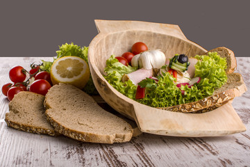 Vegetables, bread and lemons to prepare meals in a wooden bowl